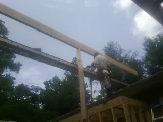 Carpenter setting a ridge beam over a new addition frame — Ice Dam Removal by Roofing Brothers in Plevna