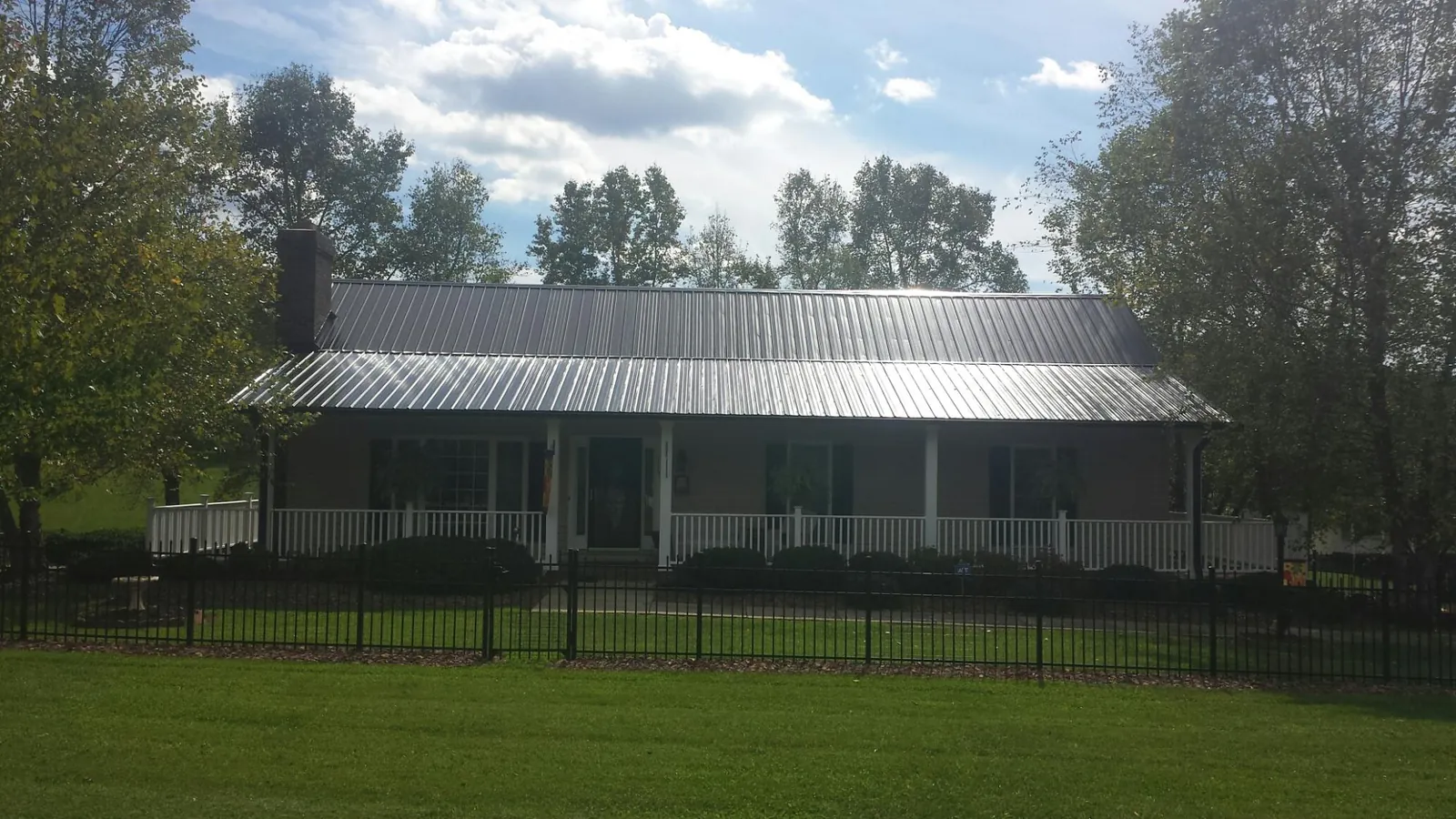 Gray metal roof on a brick ranch with a full width front porch — Gutter Guard Installation work by our crew in Plevna