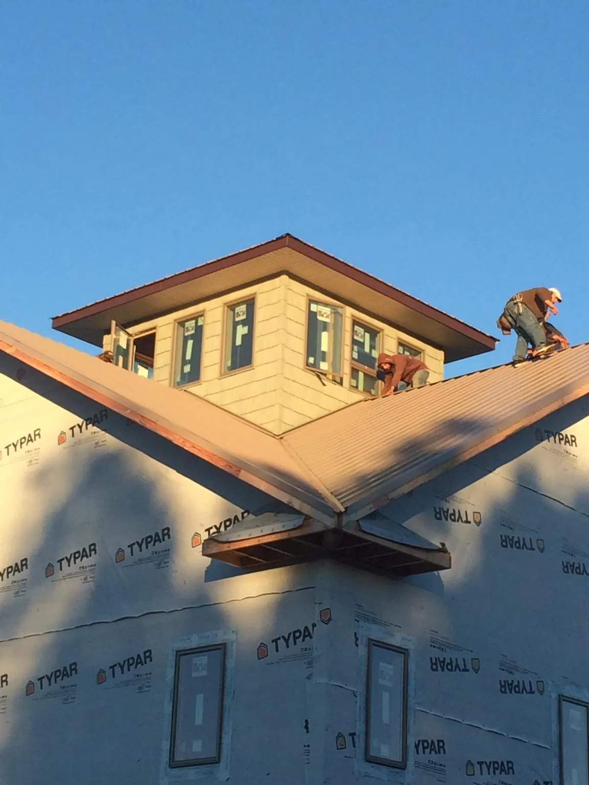 Roofers working around a rooftop cupola on a new metal roof at sunset — Roof Waterproofing in Plevna by Roofing Brothers